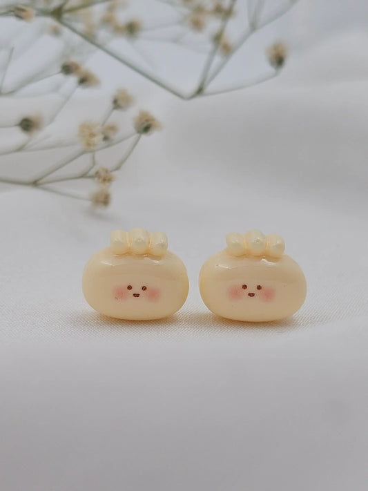 Pair of cute, round earrings with facial expressions on a light background