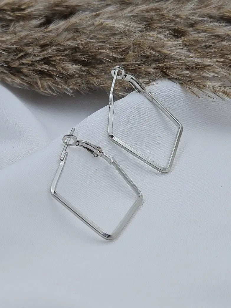 Silver square hoop earrings on a light gray surface with a fur background