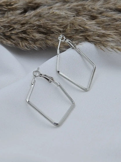 Silver square hoop earrings on a light gray surface with a fur background