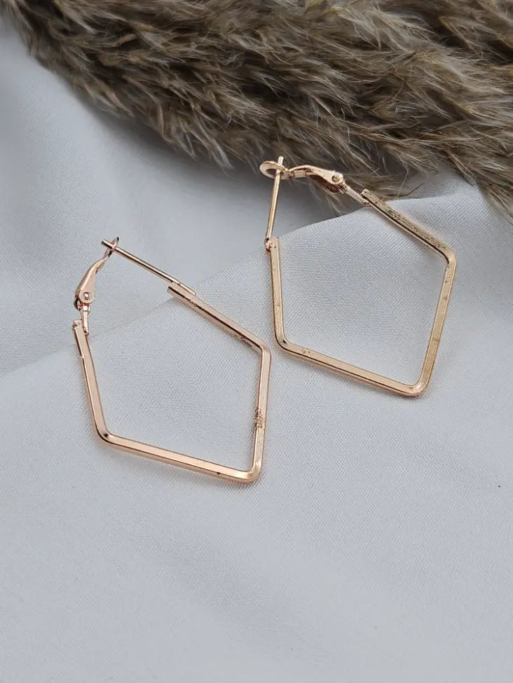 Rose gold hoop earrings on a light gray surface with fur in the background