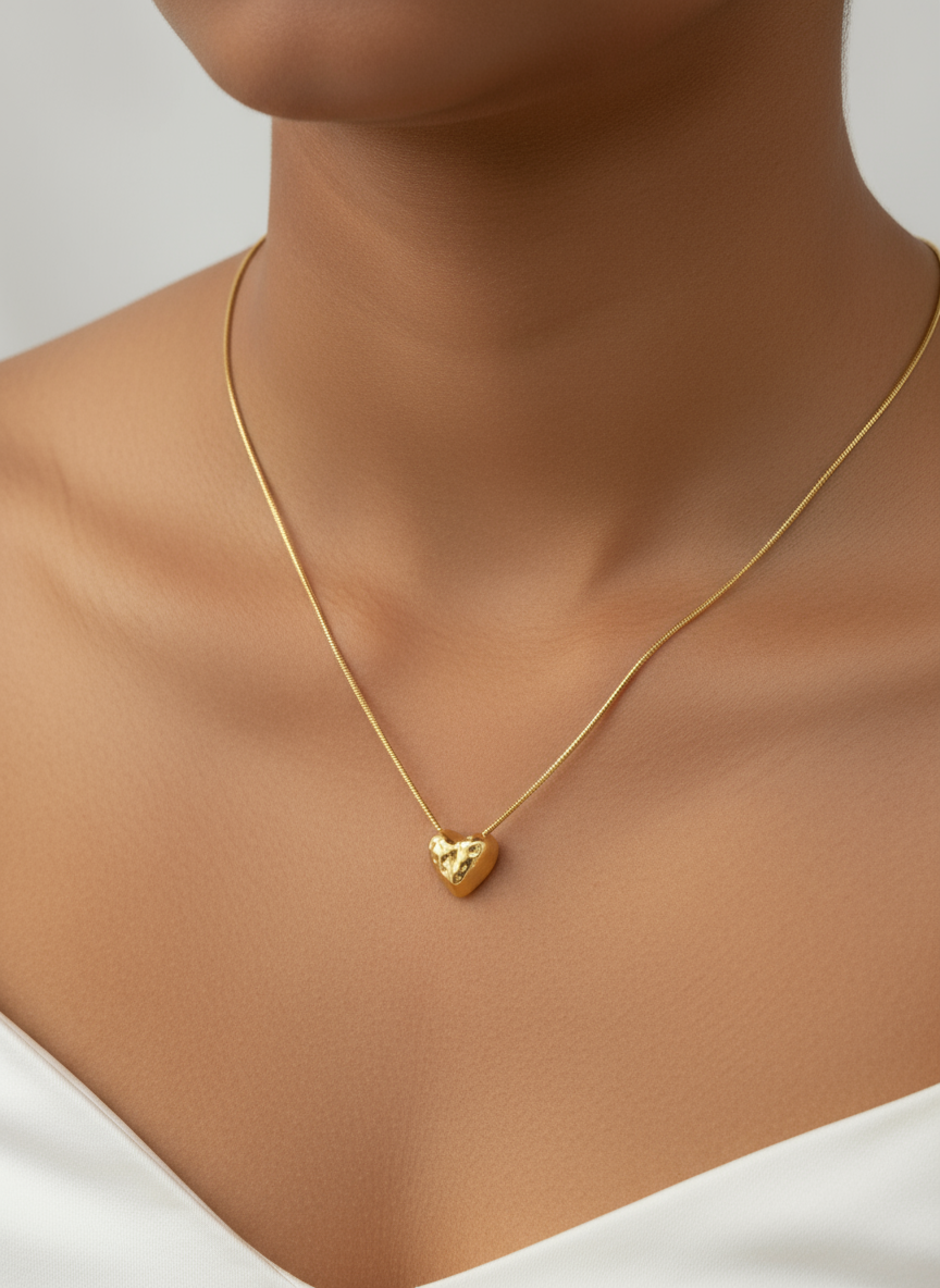 Gold heart-shaped necklace on a mannequin with a neutral background