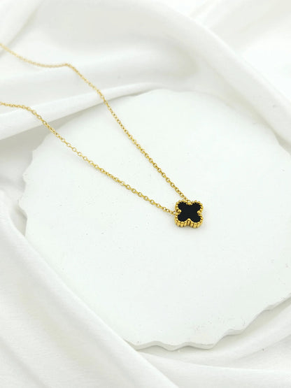 Gold necklace with a black pendant on a white fabric background