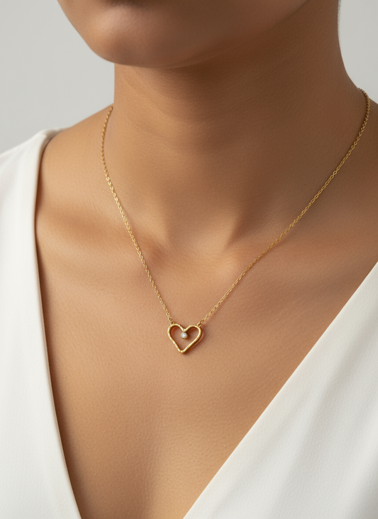 Gold heart-shaped necklace on a white fabric background