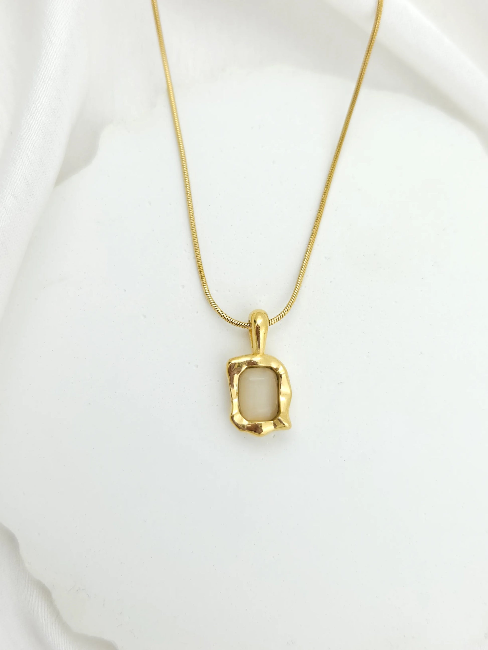Gold necklace with a pendant on a white background