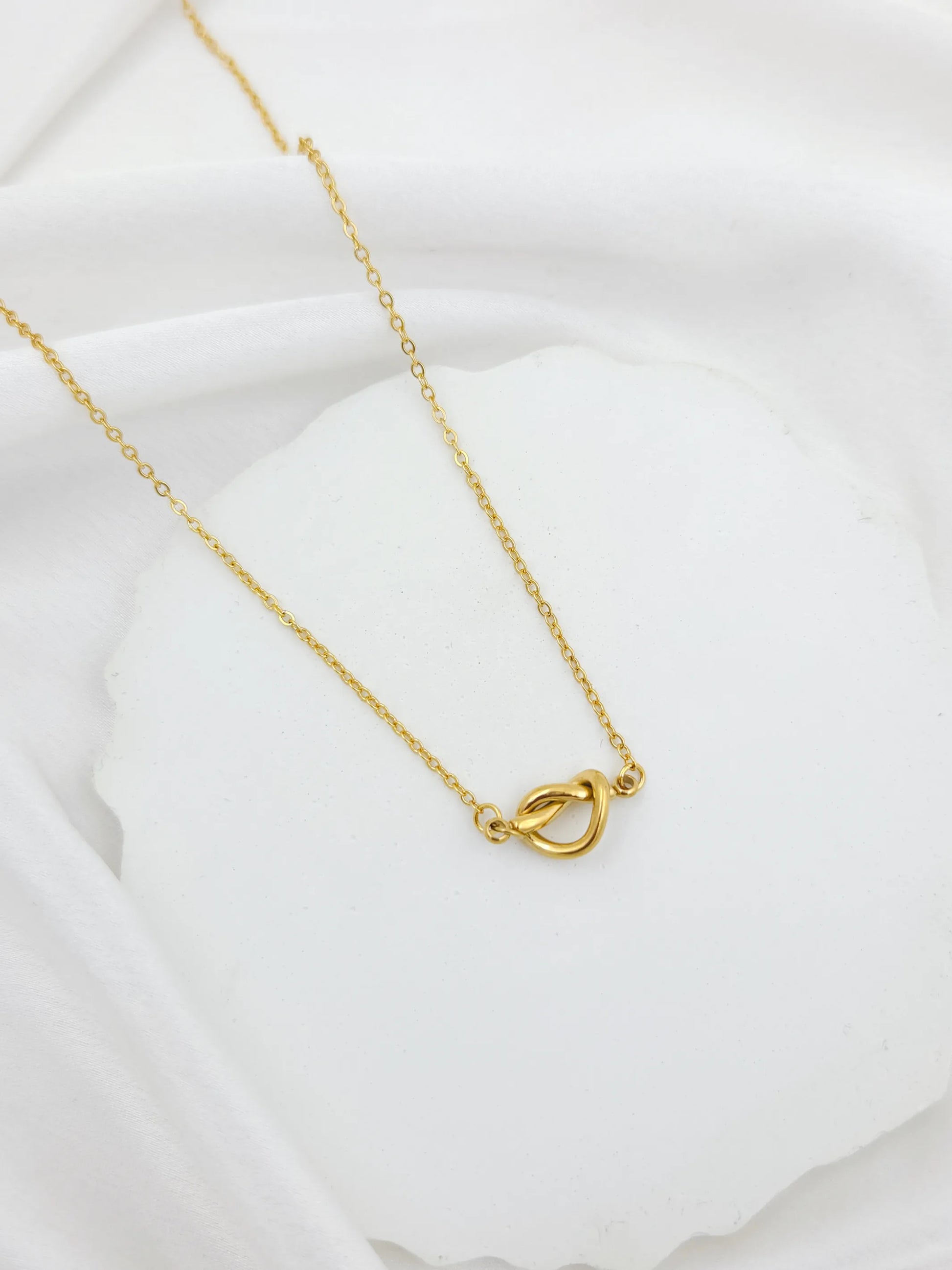 Gold necklace with a heart-shaped clasp on a white background