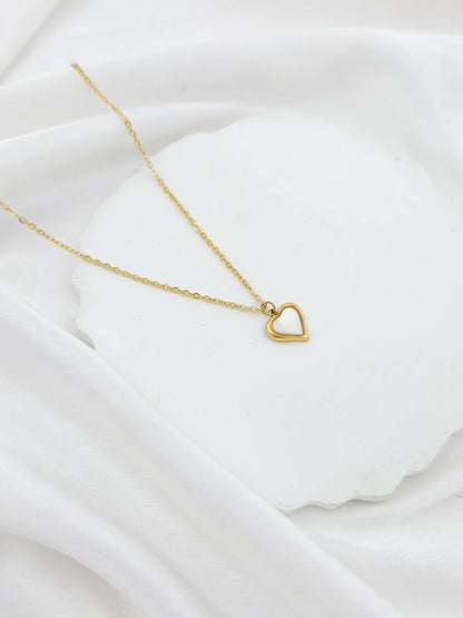 Gold necklace with a heart pendant on a white fabric background